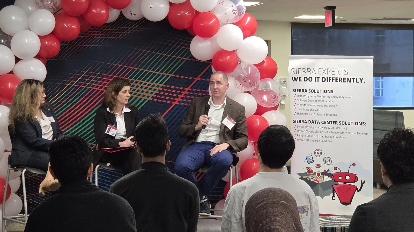 Panel discussion on stage, with a Sierra Experts banner beside the balloon arch