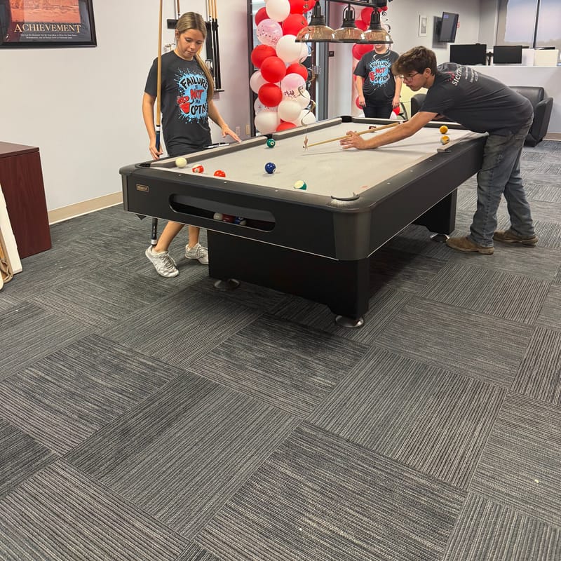 Team members playing pool in the office during the celebration