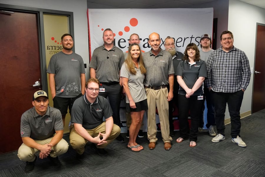 The Sierra Experts team, most in matching Sierra Experts shirts, gathered in front of the company banner at the office