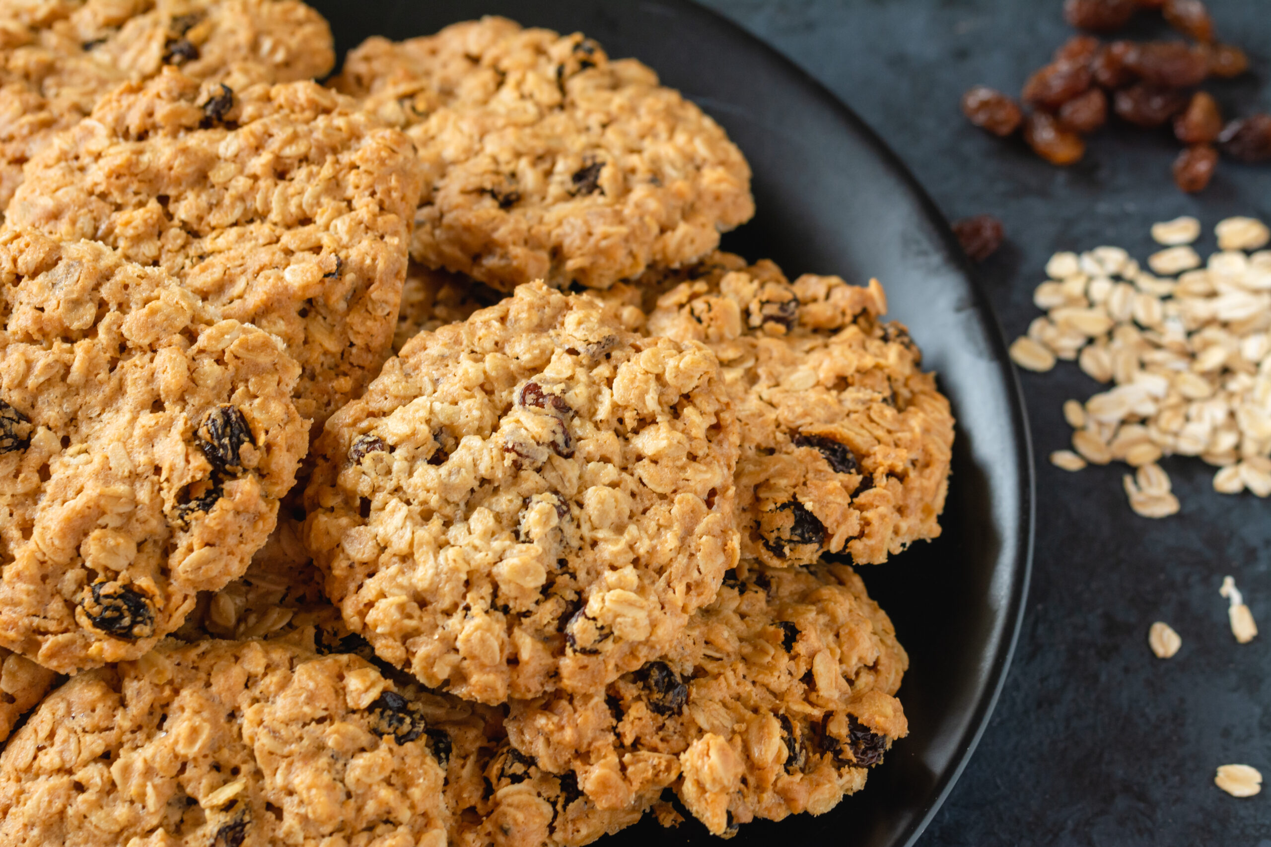 a pile of oatmeal raisin cookies on a dark background