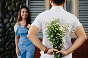 a man facing a woman with flowers behind his back