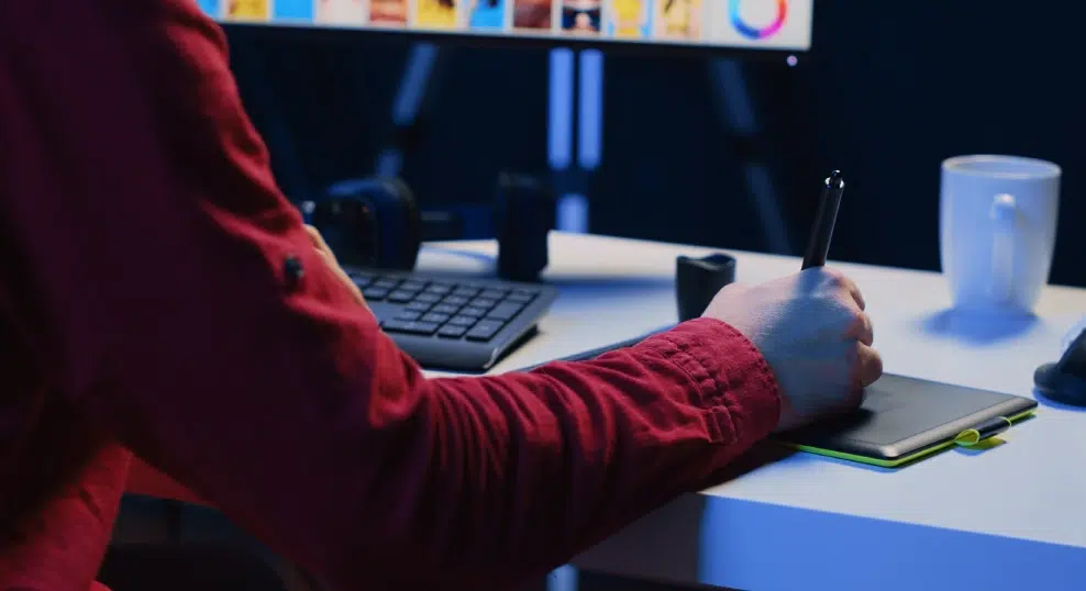 Designer working at a desk with a drawing tablet and monitor